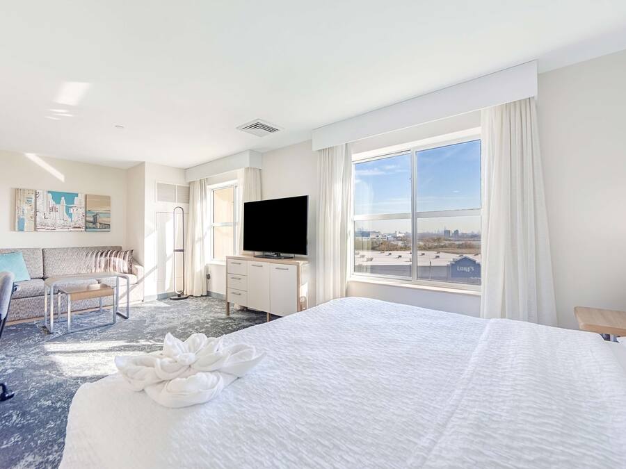 Habitación de hotel con una cama grande, un televisor de pantalla plana, un sofá, un escritorio y vistas a la ciudad.