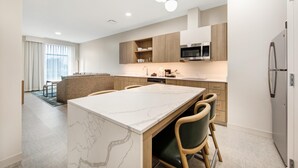 Une cuisine moderne dotée d’un îlot en marbre, de meubles en bois et d’un four à micro-ondes encastré.