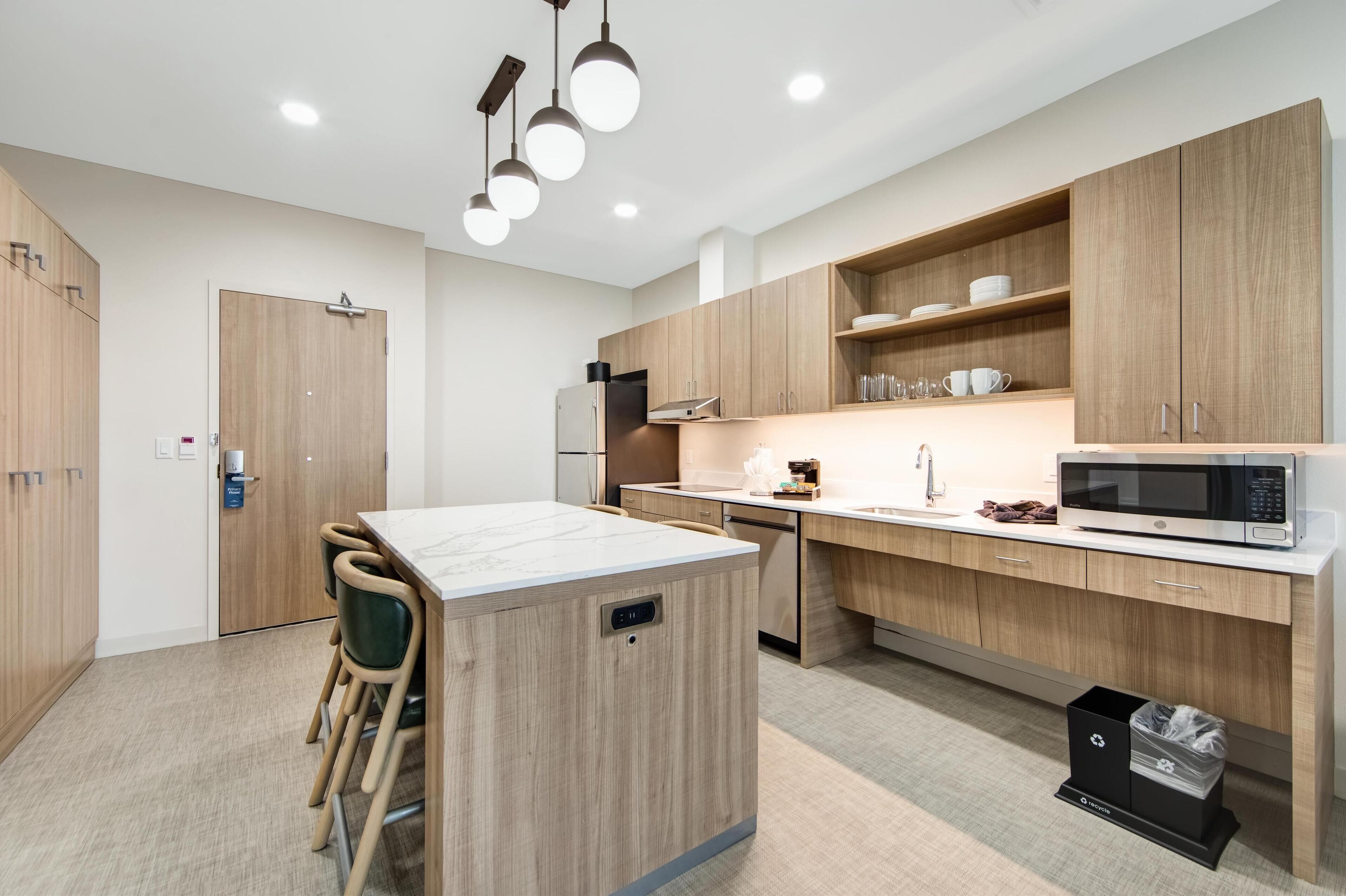 A modern kitchen with wooden cabinets, a central island, and a microwave.