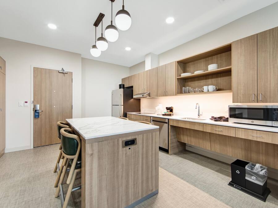 A modern kitchen with wooden cabinets, a central island, and a microwave.