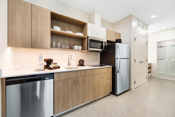 Una cocina moderna con armarios de madera, electrodomésticos de acero inoxidable y encimera blanca.