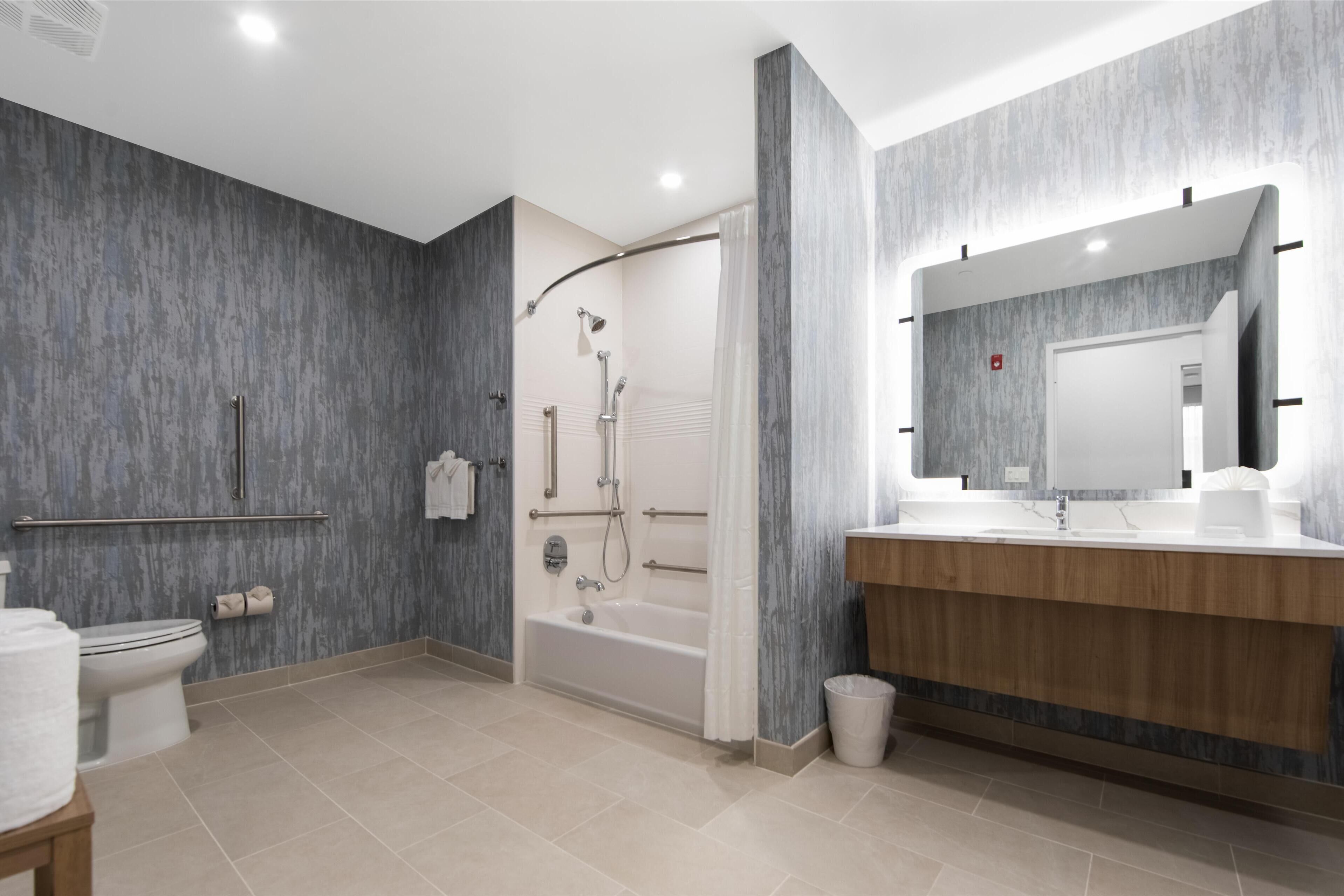 A modern bathroom with a bathtub, shower, and toilet.