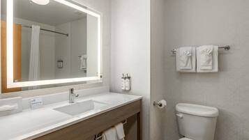A modern bathroom with a large mirror, two sinks, a toilet, and a towel rack.