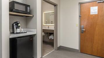 A compact kitchenette with a microwave, coffee machine, and refrigerator.