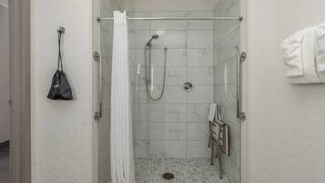 A walk-in shower with a glass door, a towel rack, and a showerhead.