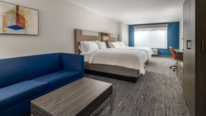 A hotel room with a blue sofa, two beds, a desk, and a large window. - Holiday Inn Express Hotel & Suites Vancouver Mall by IHG (Vancouver)