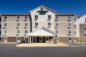 Ein mehrstöckiges Hotel mit zentralem Eingang und überdachtem Parkplatz.