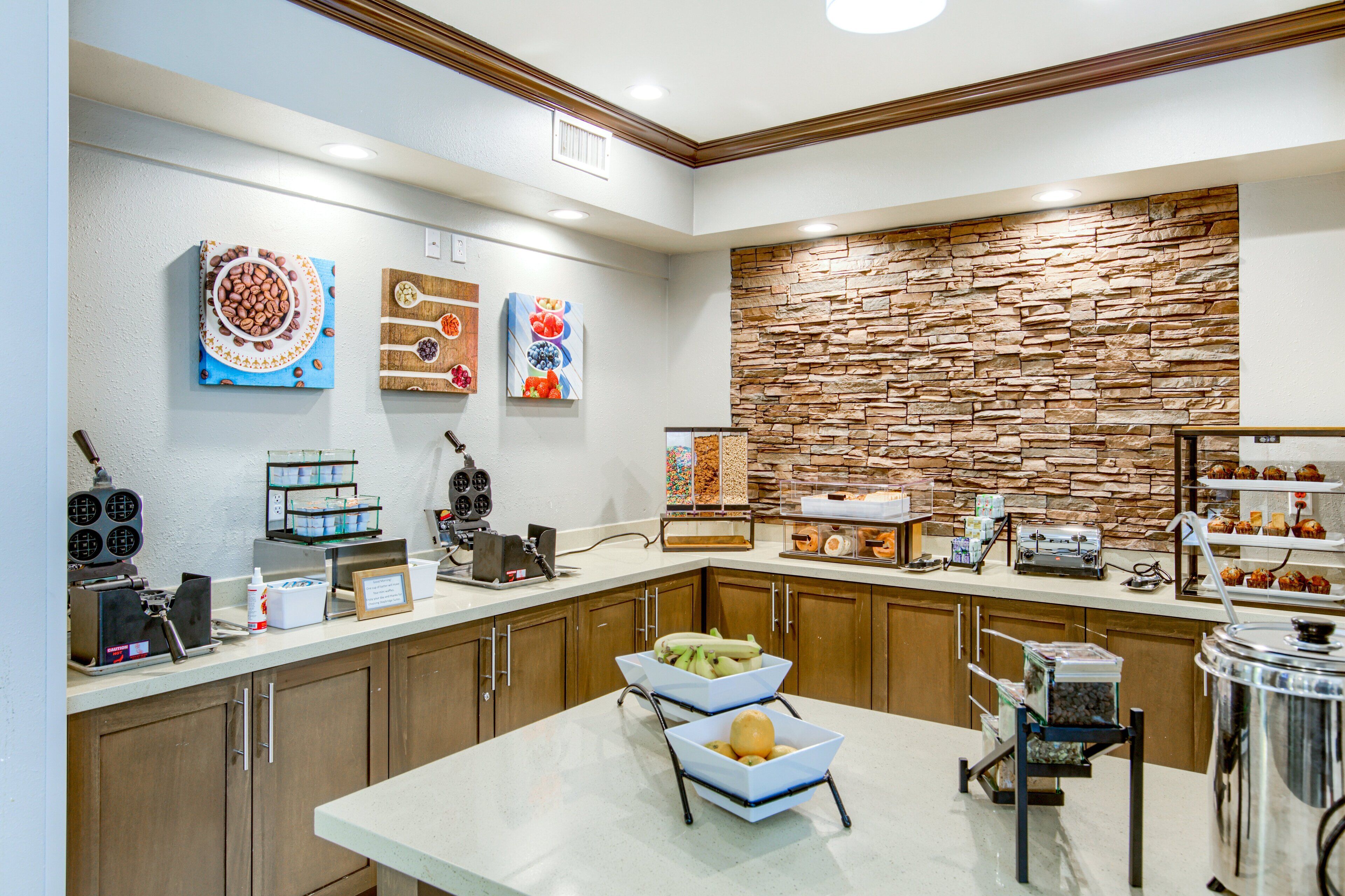 A modern kitchen with wooden cabinets, a stone accent wall, and various appliances.