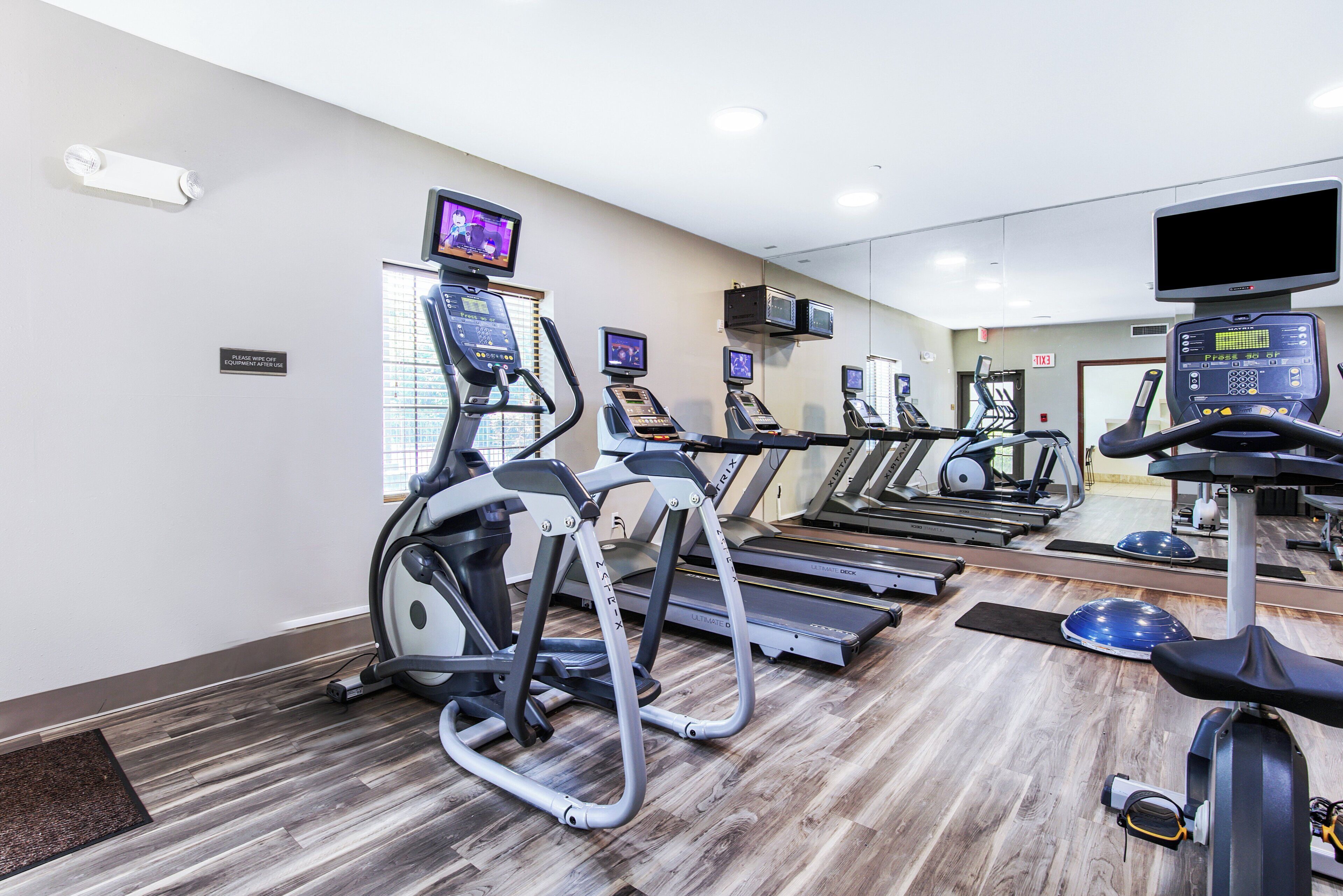 A gym with treadmills, elliptical machines, and exercise bikes, equipped with digital screens and heart rate monitors.