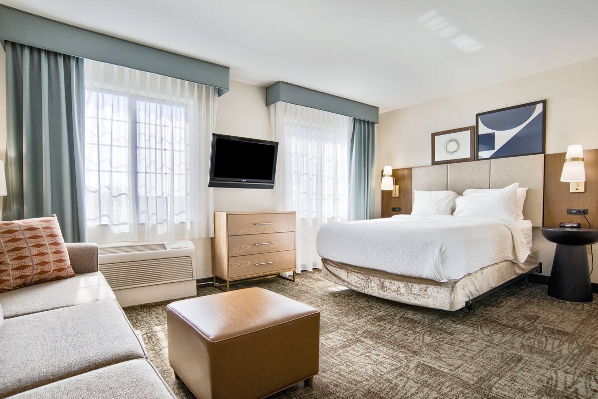 Een hotelkamer met een bed, een dressoir, een televisie en een bank.