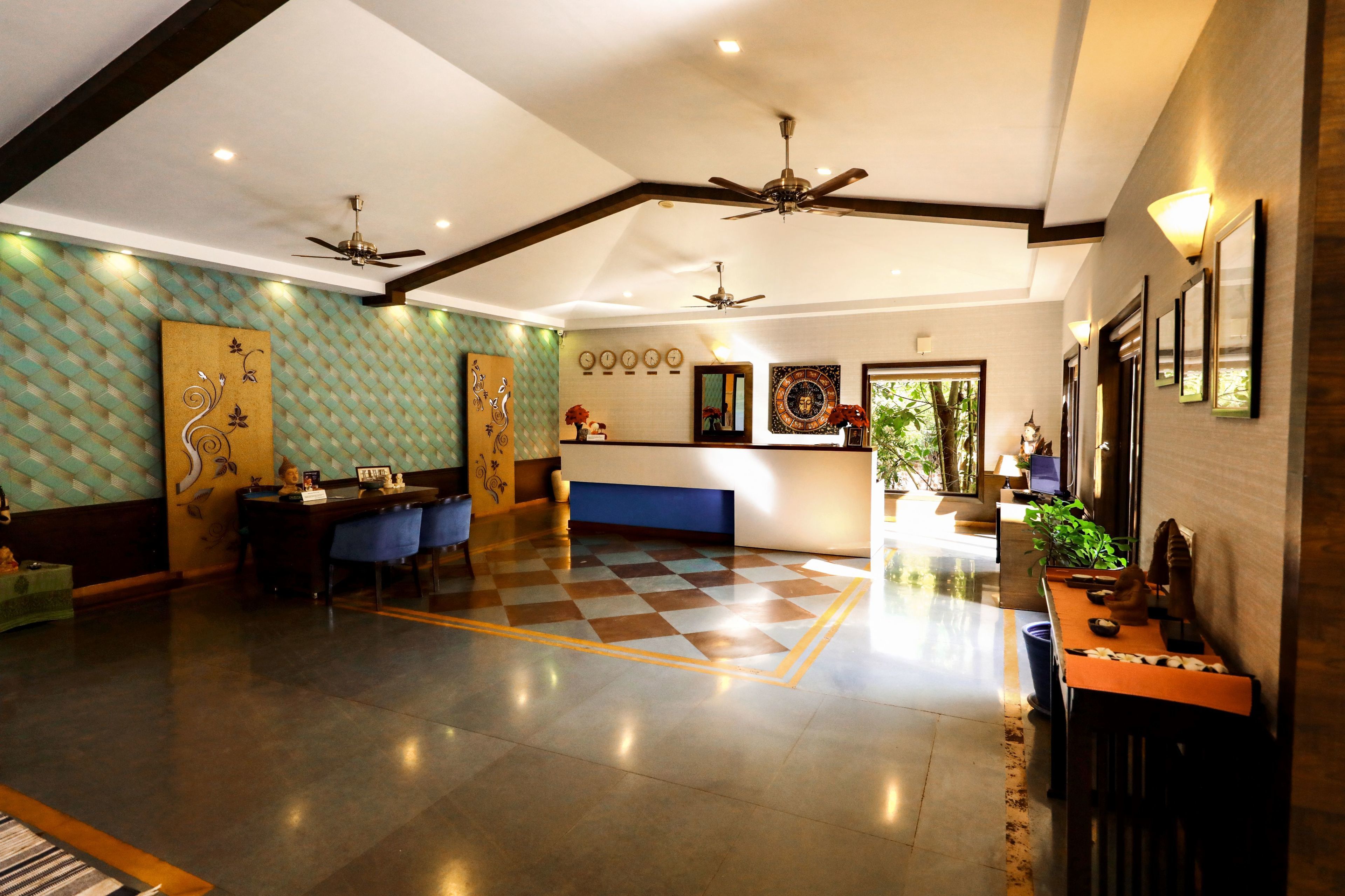A spacious lobby with a checkered floor, ceiling fans, and a reception desk.