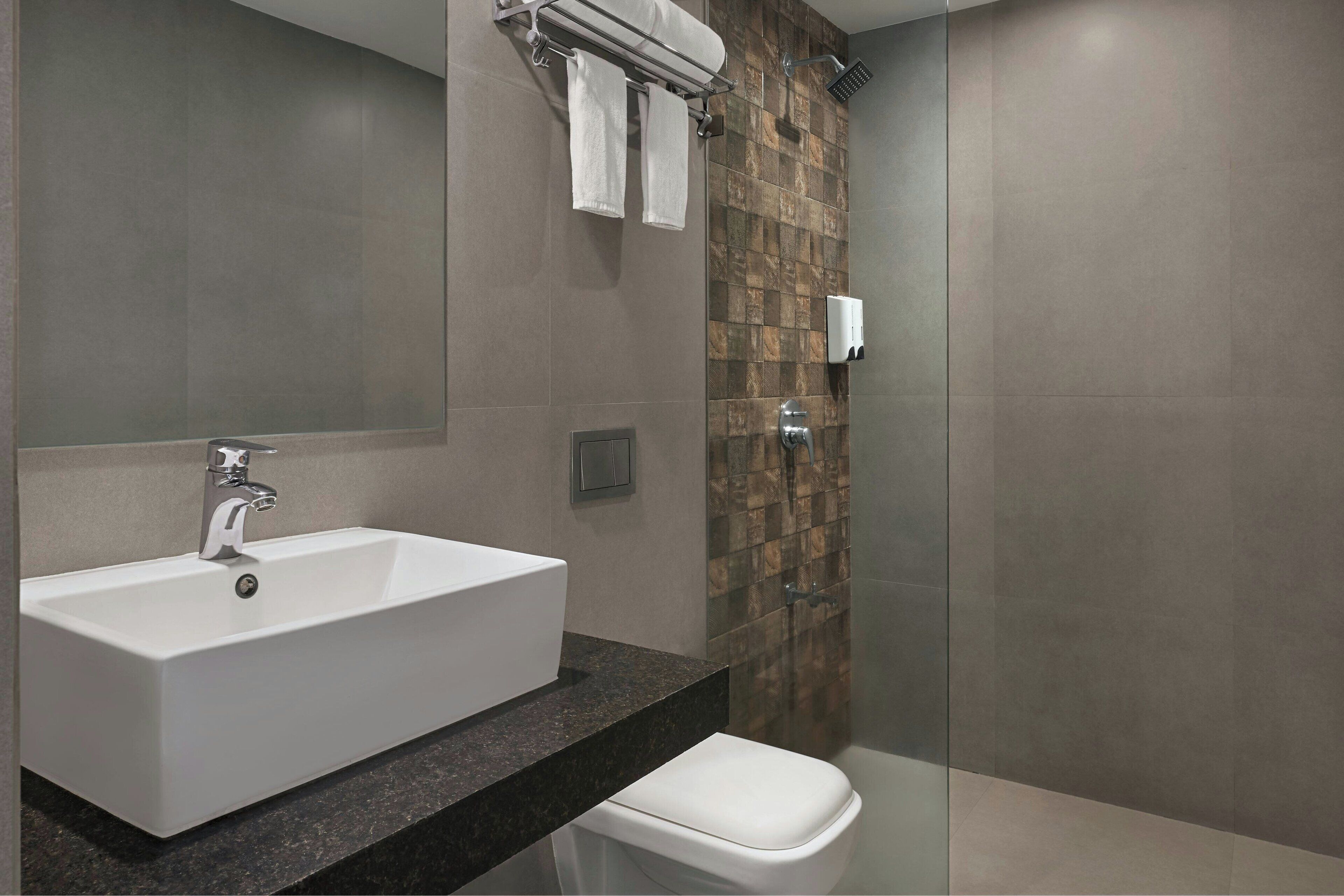 A modern bathroom with a rectangular sink, a toilet, and a shower area.