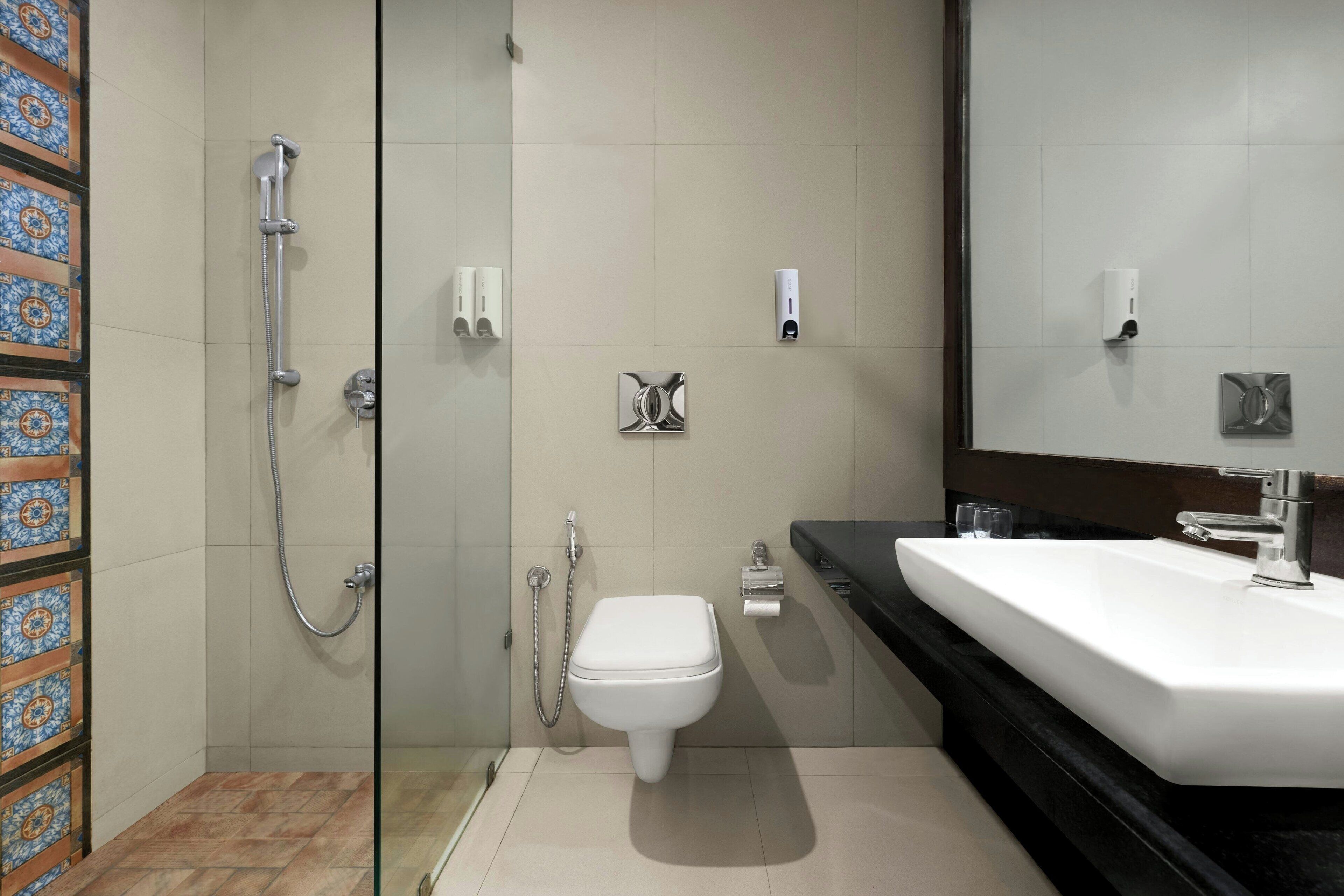 Een moderne badkamer met een douchecabine van glas, een wit toilet en een zwart aanrecht met een wastafel.