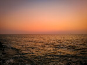 Ein Sonnenuntergang über einem ruhigen Meer mit leichten Wellen.