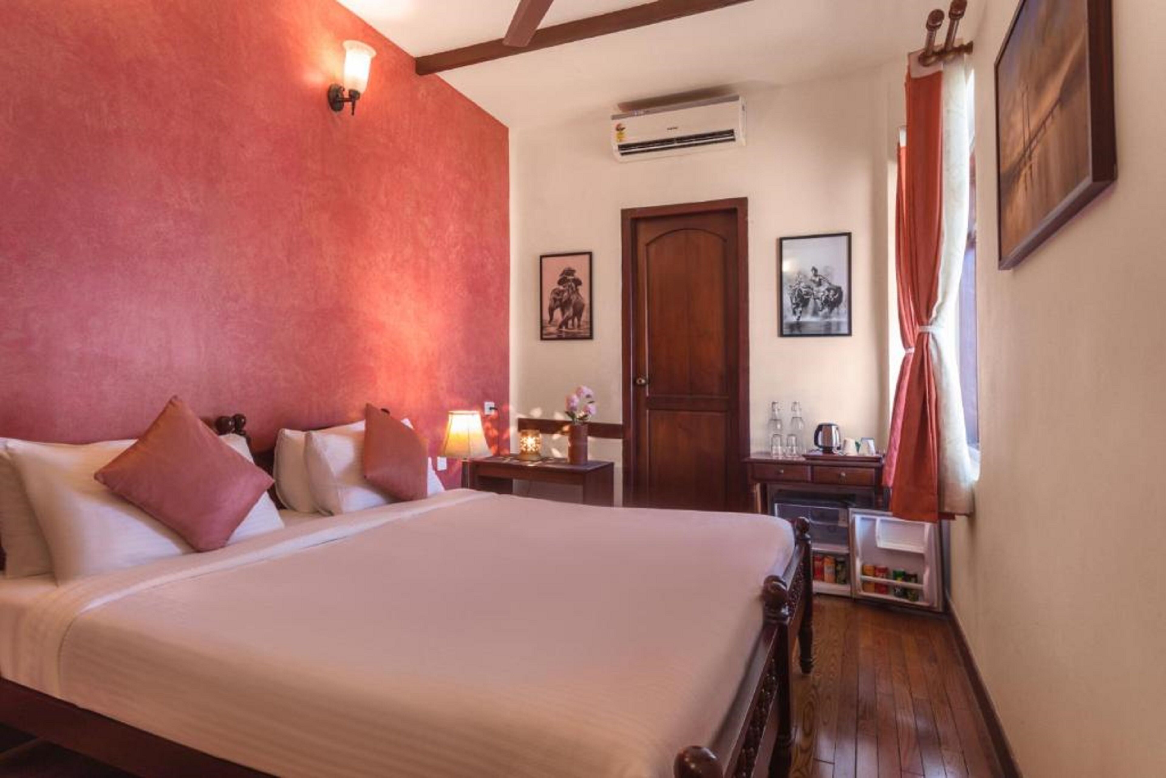 Une chambre d’hôtel avec un grand lit, un bureau, une armoire et une fenêtre avec des rideaux.
