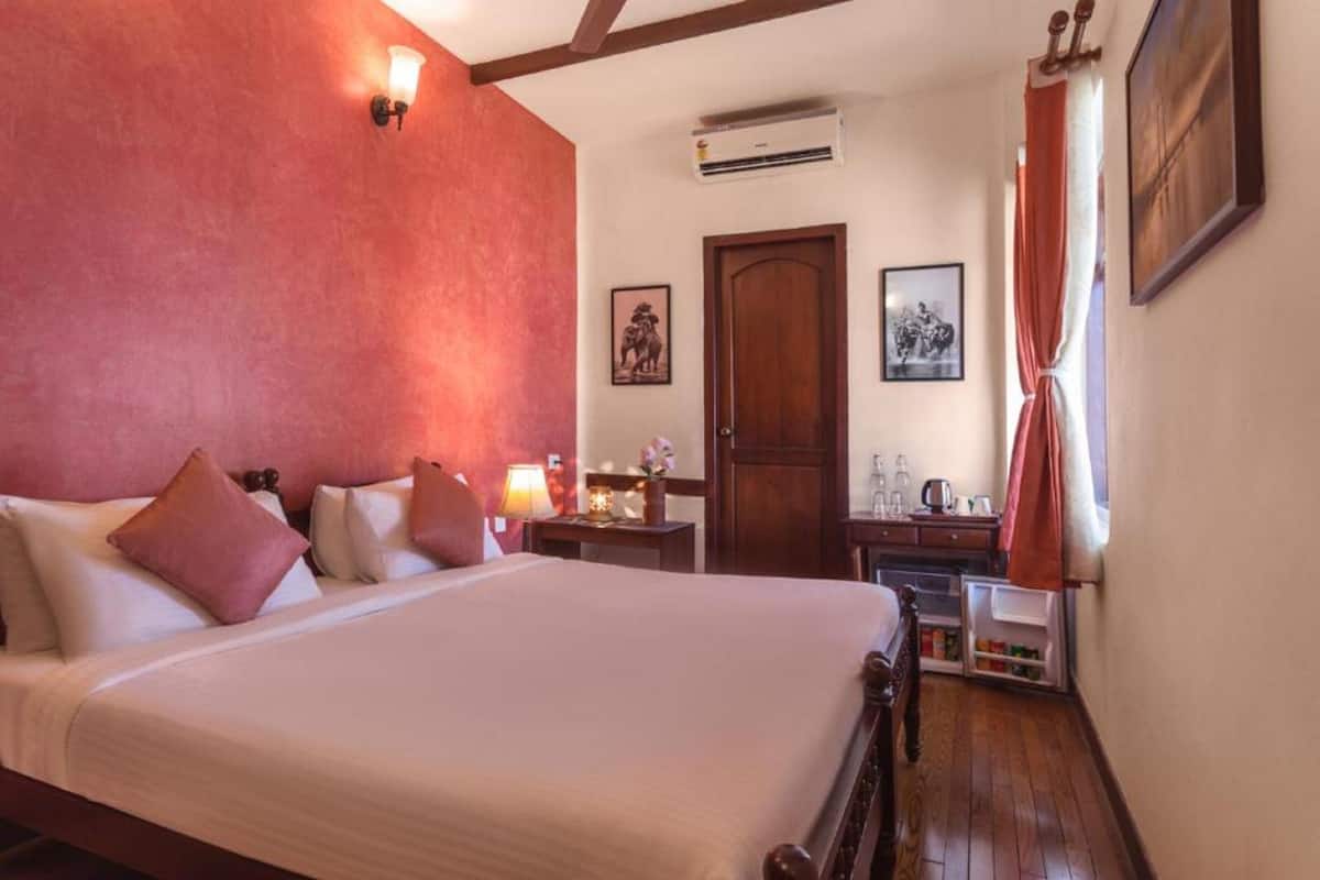 Une chambre d’hôtel avec un grand lit, un bureau, une armoire et une fenêtre avec des rideaux.