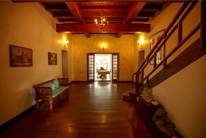 A spacious hallway with a wooden bench, a staircase, and a chandelier.