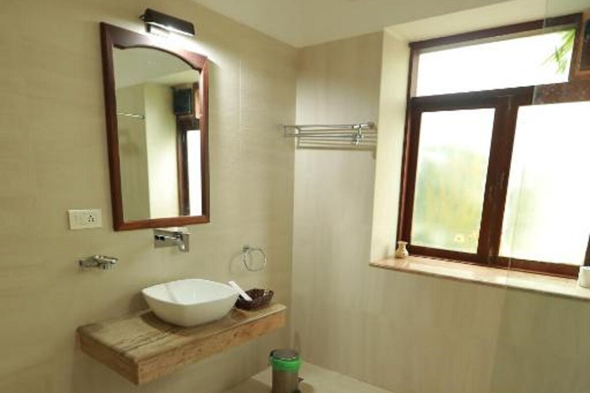 A bathroom with a white sink, mirror, and window.