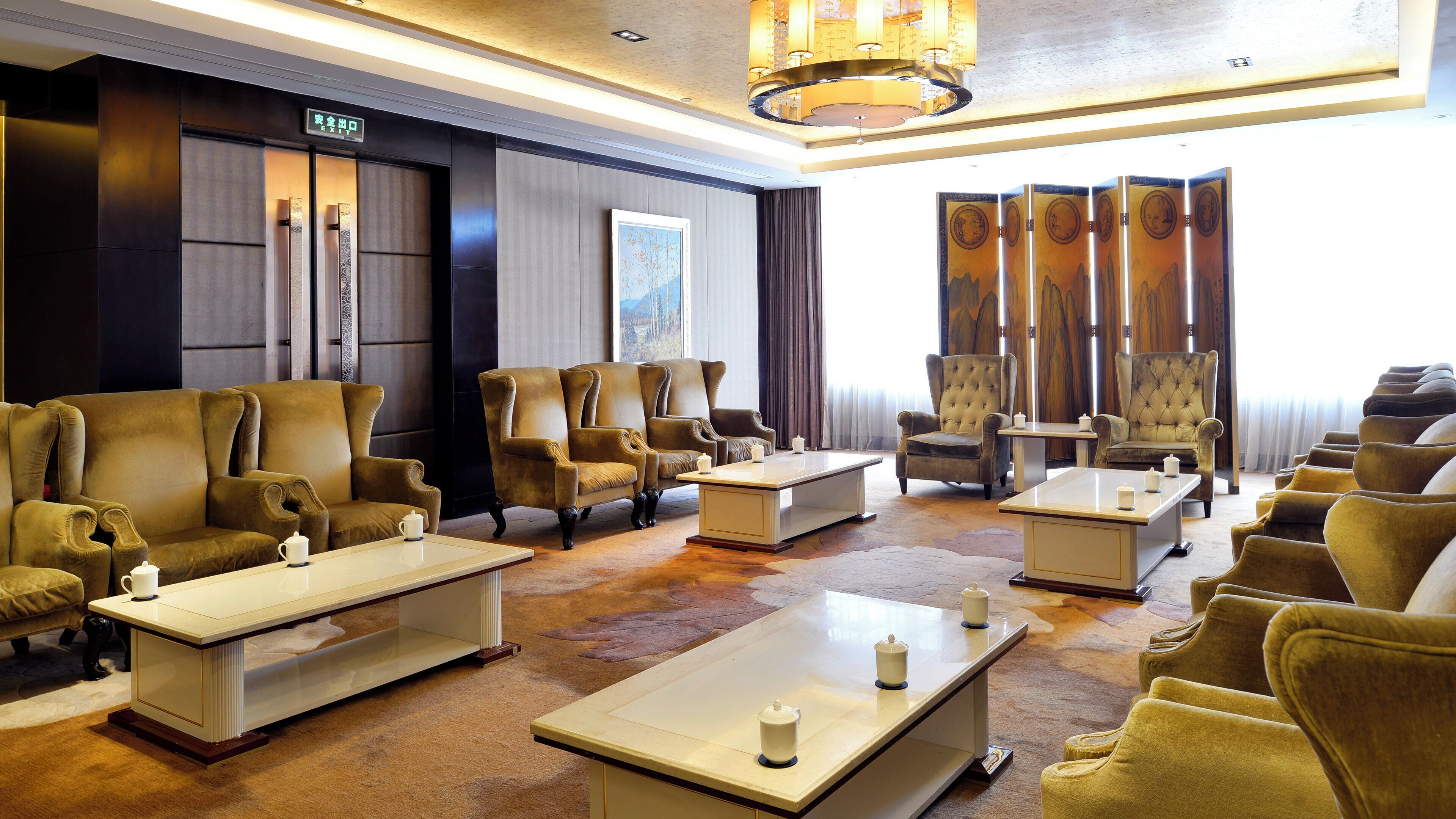 A hotel lobby with multiple seating areas, including sofas and armchairs, arranged around coffee tables.
