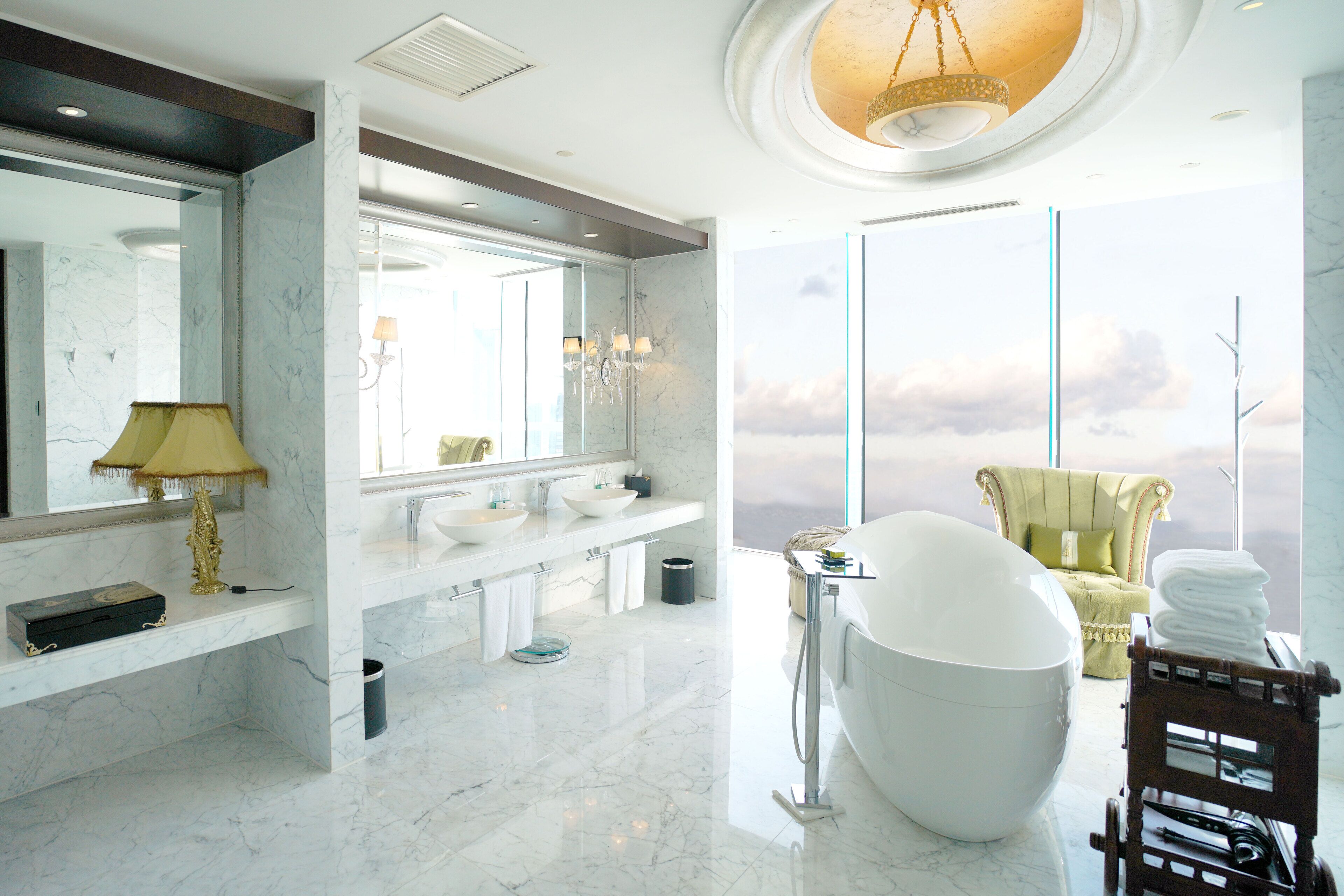 Une salle de bain moderne avec une grande baignoire, un meuble-lavabo doté de deux vasques et une chaise près de la fenêtre.