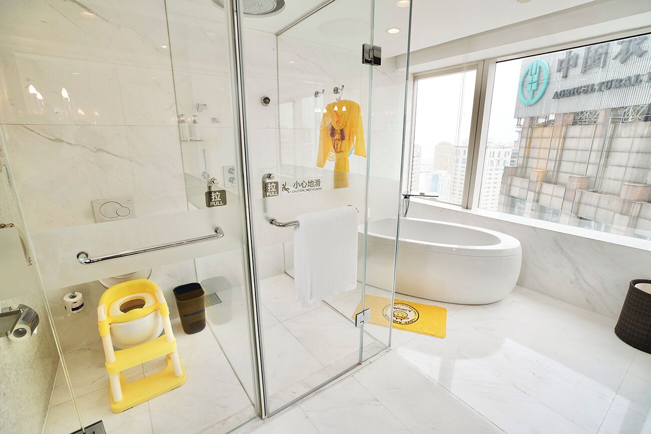 Un baño moderno con cabina de ducha de vidrio, una bañera blanca y un toallero amarillo.