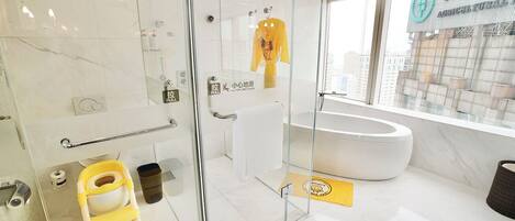 Un baño moderno con cabina de ducha de vidrio, una bañera blanca y un toallero amarillo.
