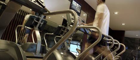 A treadmill in a gym with a digital display and a mirror.