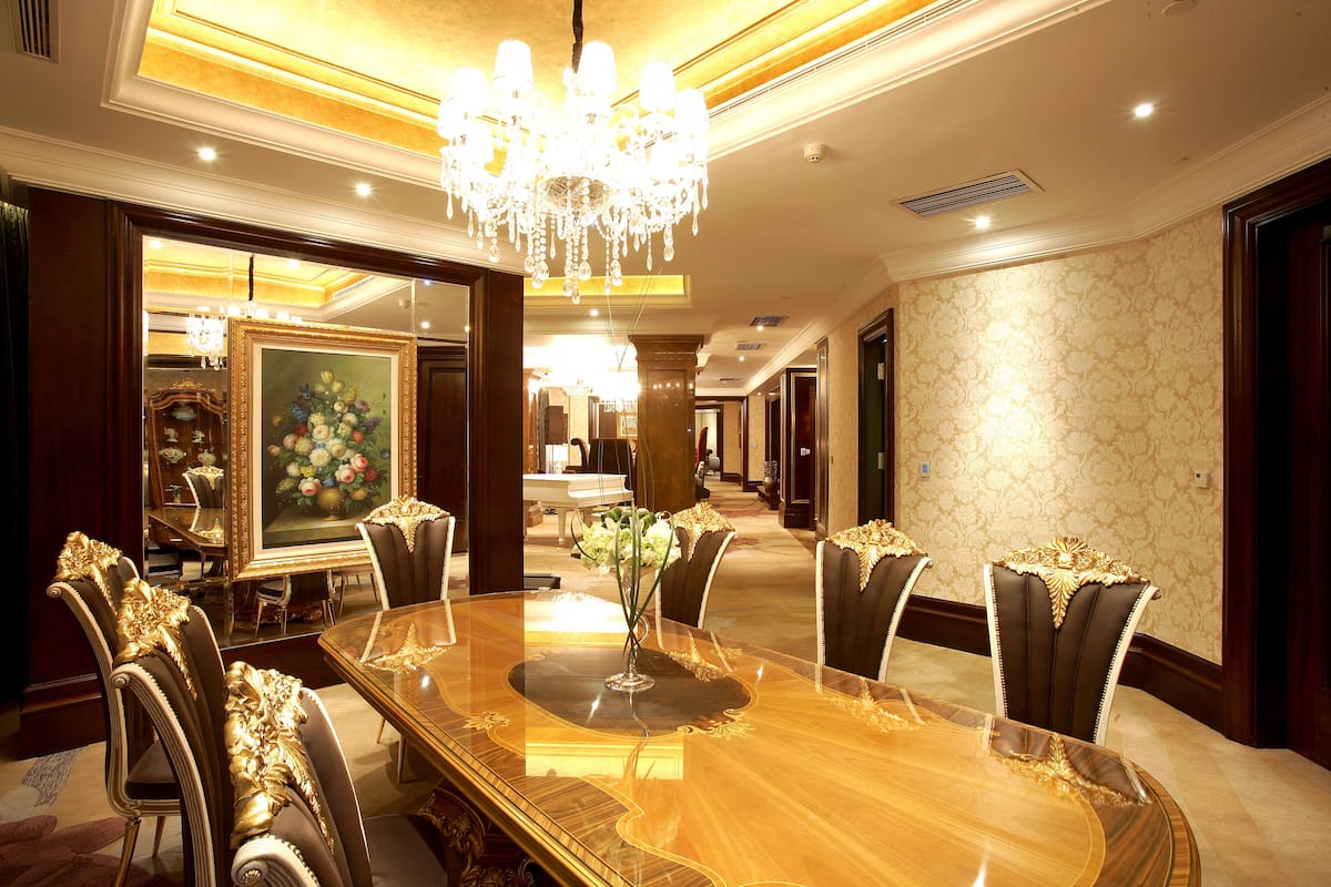 A luxurious dining area with a large wooden table, ornate chairs, and a chandelier.