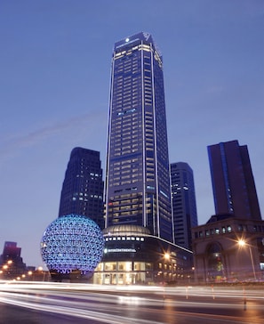 Un immeuble de grande hauteur portant l’inscription « INTERCONTINENTAL », entouré d’autres bâtiments imposants et agrémenté d’une installation lumineuse sphérique.