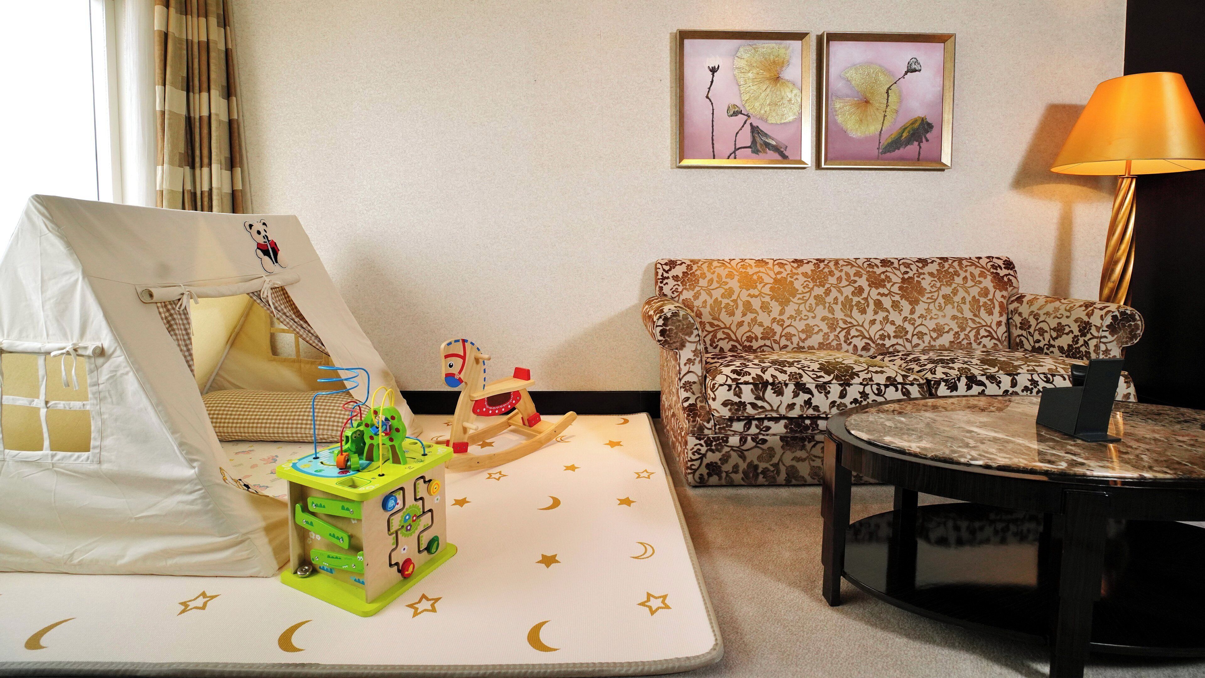 A cozy room with a play tent, a patterned sofa, a small table, and artwork on the wall.