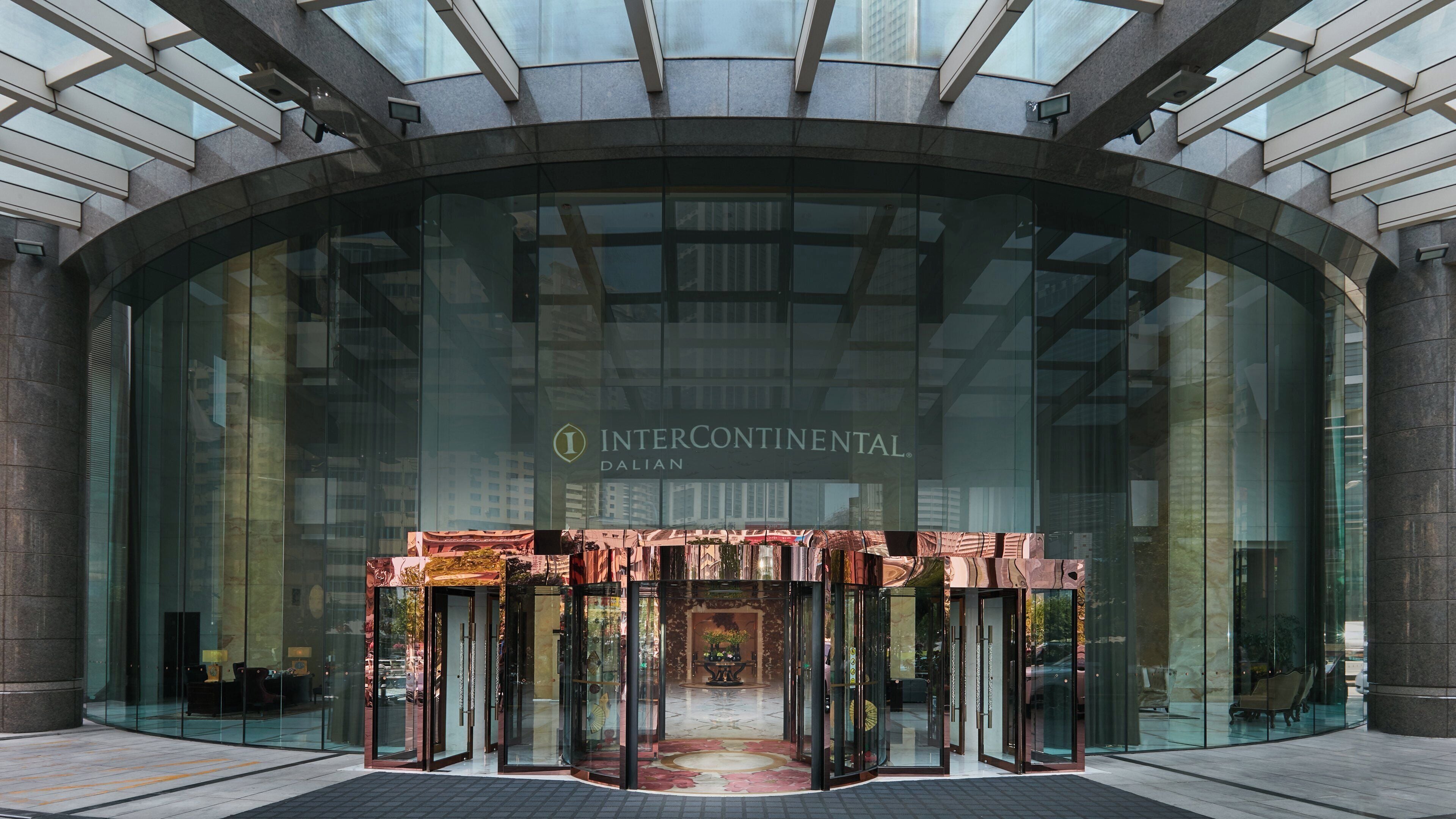 Une entrée moderne avec une façade en verre, une porte tournante centrale et le nom « INTERCONTINENTAL » bien visible.