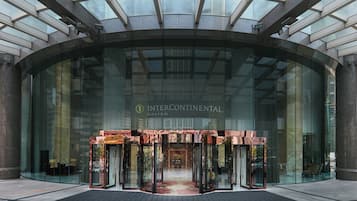 Une entrée moderne avec une façade en verre, une porte tournante centrale et le nom « INTERCONTINENTAL » bien visible.