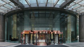 Fachada de um edifício moderno com paredes de vidro, porta giratória central e a inscrição 'INTERCONTINENTAL'.