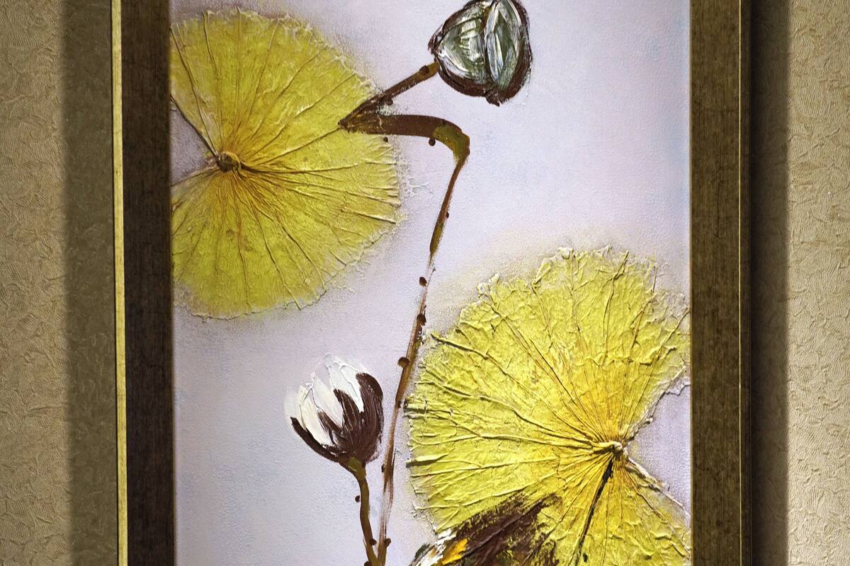 A framed artwork of dried flowers on a wall.