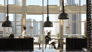 Un intérieur moderne avec de grandes fenêtres, de nombreux espaces de détente et des luminaires suspendus.
