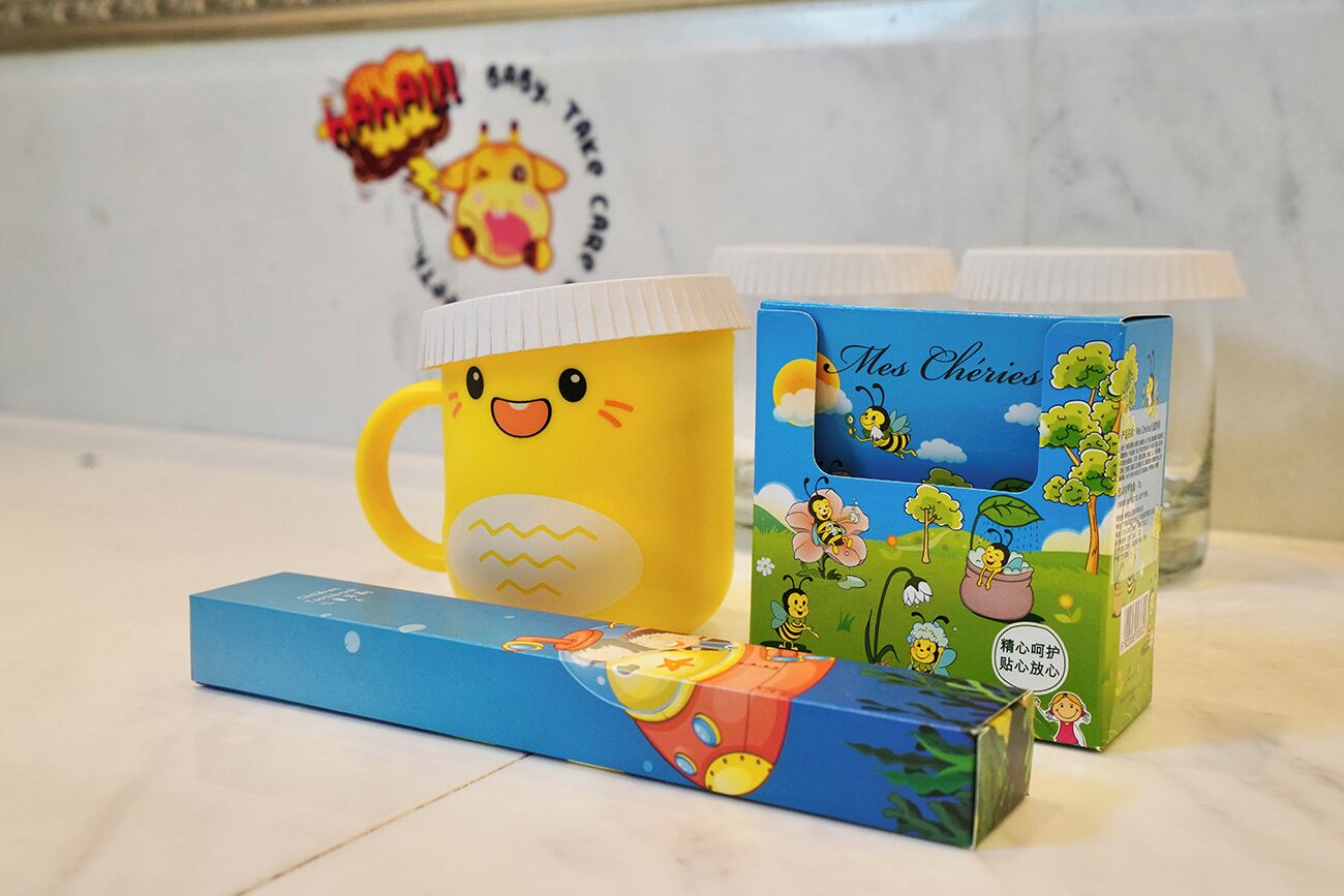 A kitchen counter with a yellow mug, a blue box, and a green box with a bee design.