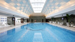An indoor swimming pool with a high ceiling, marble walls, and seating areas. - Intercontinental Dalian by IHG (Dalian)