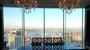 A dining area with a table and chairs, large windows with a city view, and chandeliers. - Intercontinental Dalian by IHG (Dalian)