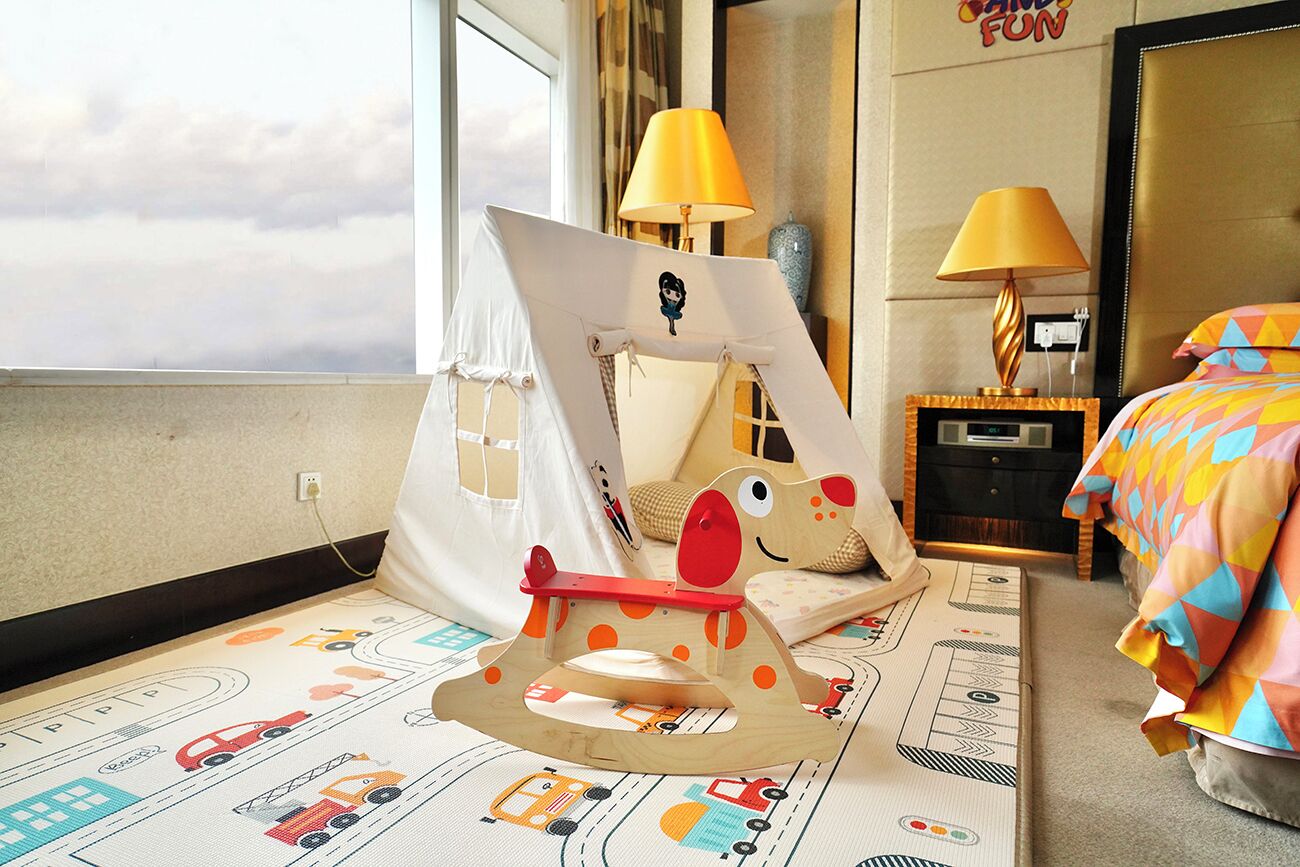 A child's play area with a tent, a rocking horse, and a bed with colorful bedding.