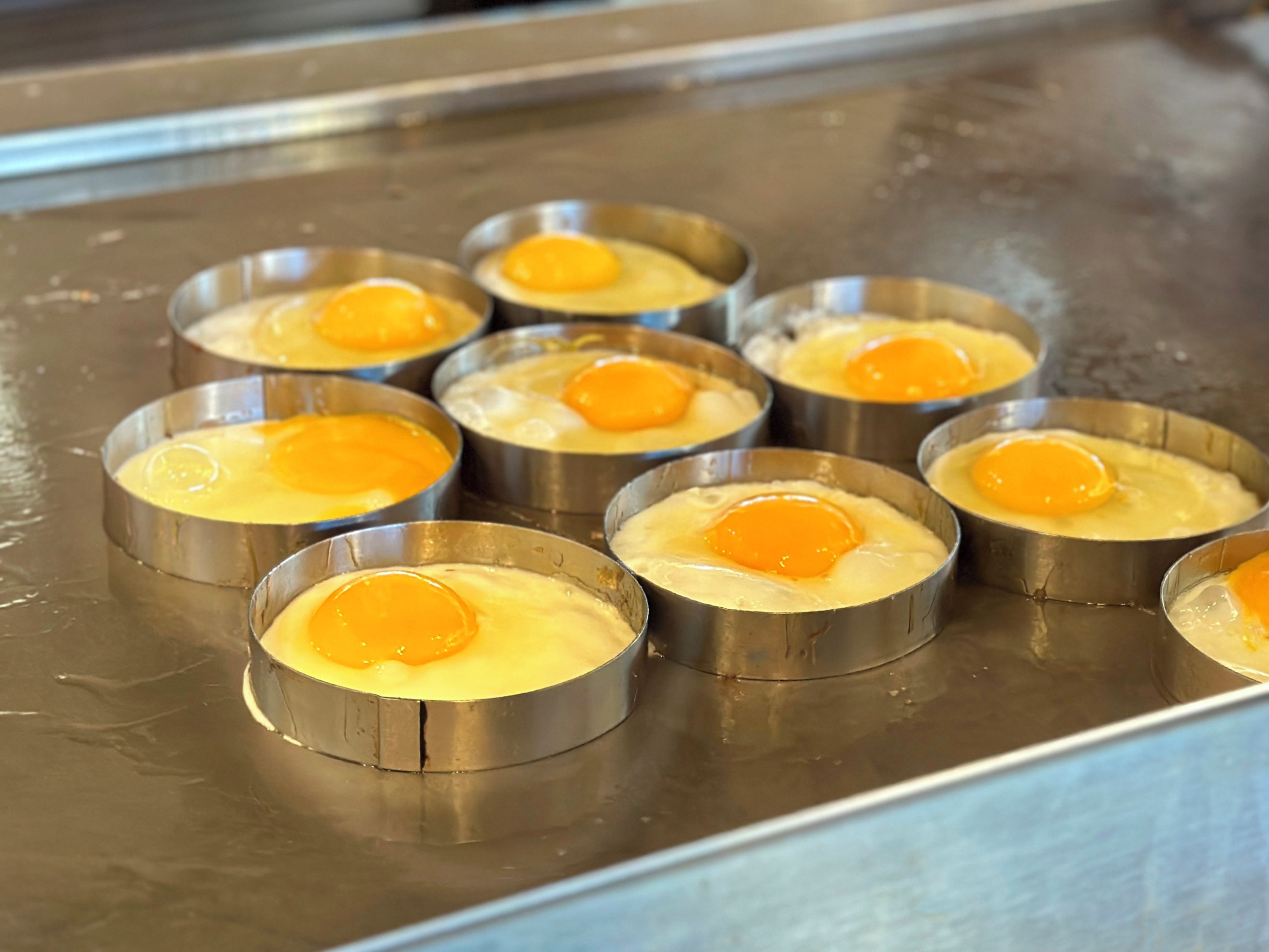 Recipientes metálicos con huevos sobre una superficie de acero inoxidable.