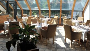 A restaurant with a high, glass ceiling and natural light. Tables are set with white tablecloths and chairs. - Bianca Resort & Spa (Kolašin)