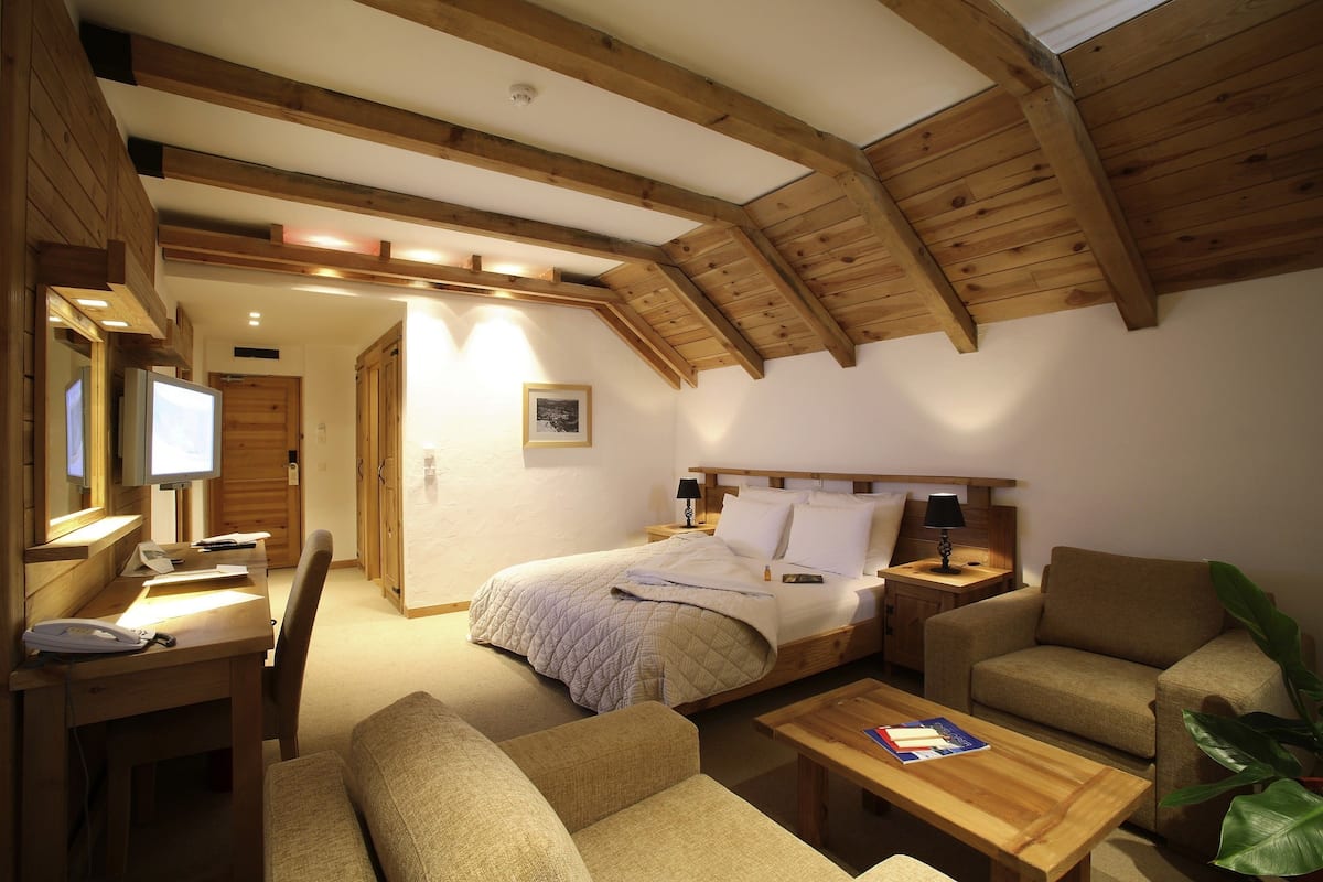 Um quarto acolhedor com uma cama, uma escrivaninha, uma cadeira e um sofá.