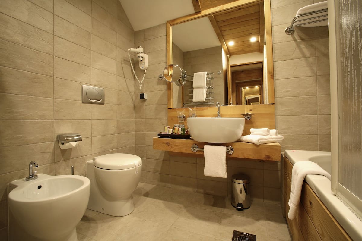 Uma casa de banho moderna com bidé, sanita, lavatório e banheira.