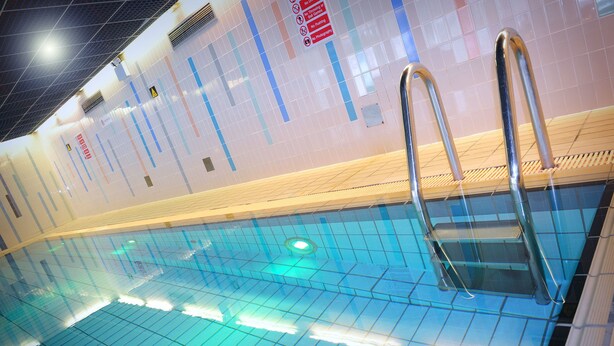 Piscina interior com paredes azulejadas e superfície de água cristalina.