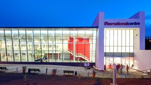 Um edifício moderno com fachada de vidro, interior vermelho e uma placa com a inscrição 