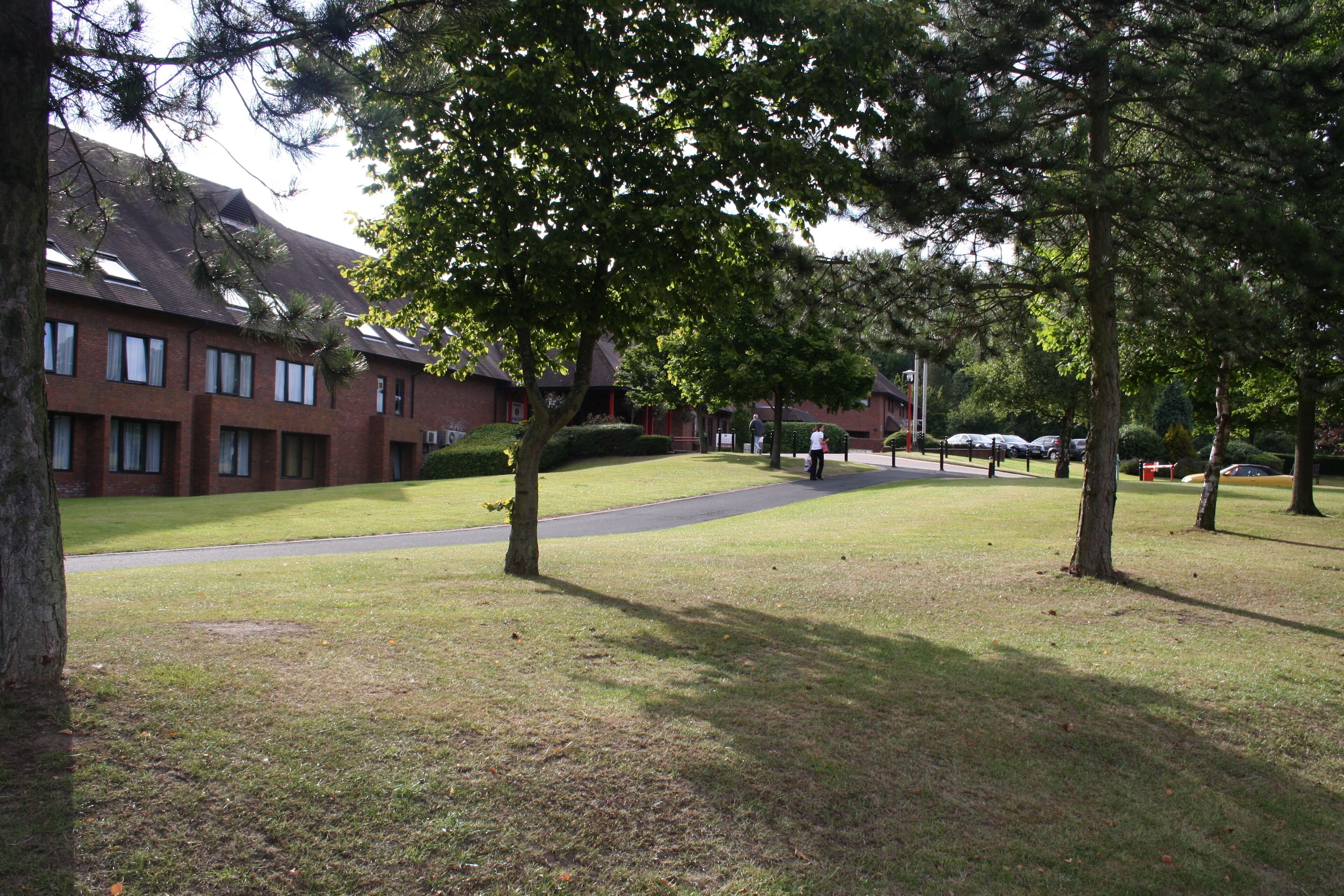 A grassy courtyard with trees, a brick building, and a pathway.