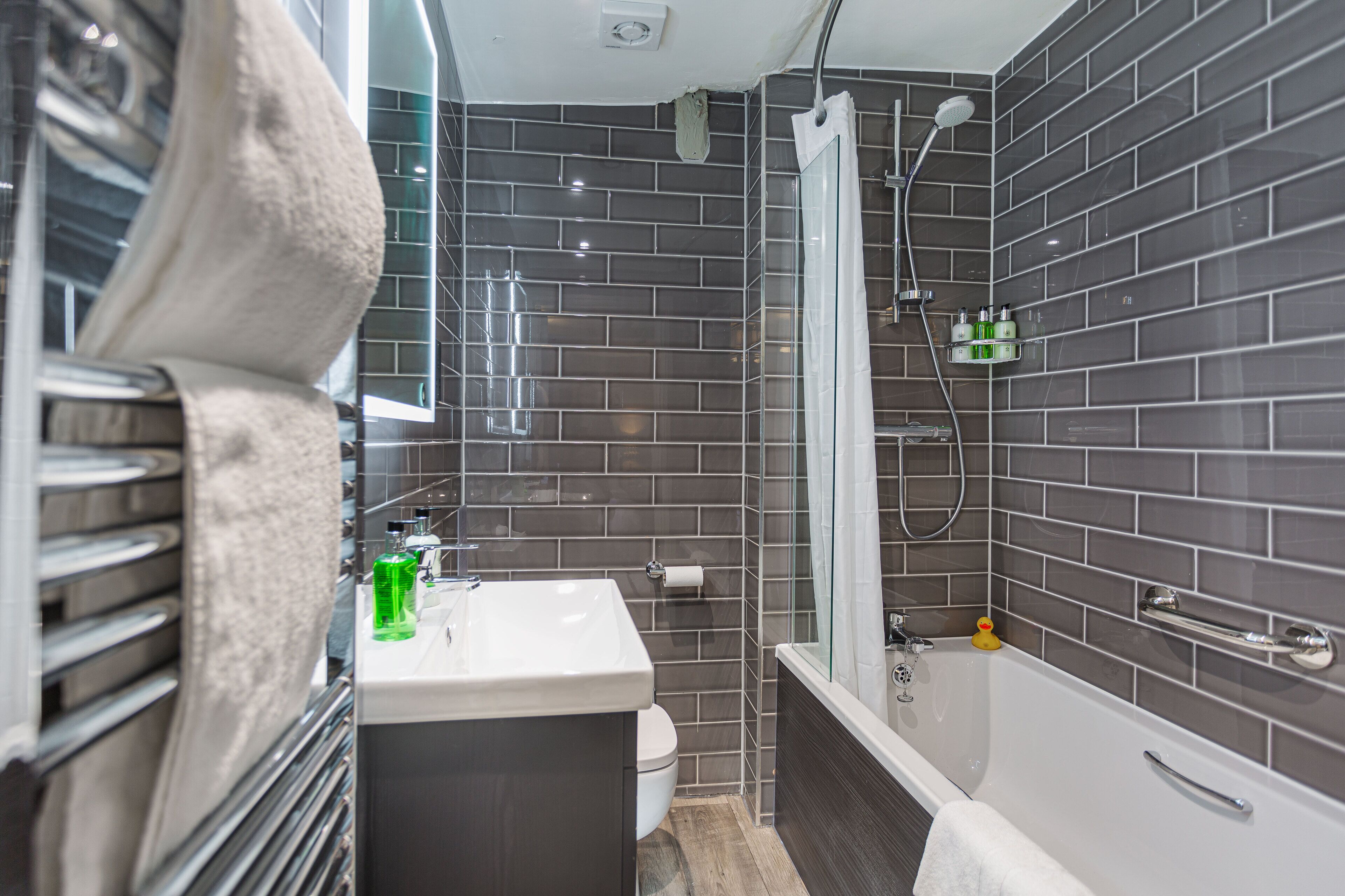 A modern bathroom with a white sink, toilet, and bathtub.