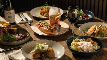 A dining table with various dishes, a bottle of wine, and a glass of red wine.