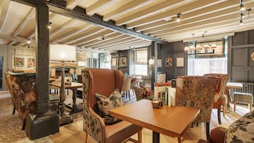 A dining area with wooden tables and chairs, a fireplace, and a view of the street.