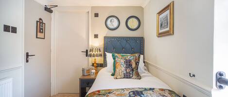 A bedroom with a bed, a nightstand, a lamp, and two framed pictures on the wall.
